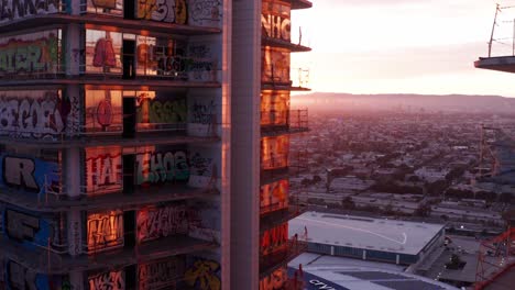Aerial-close-up-push-in-shot-of-the-unique-graffiti-art-on-the-balcony-windows-of-the-Oceanwide-Plaza-buildings-at-sunset-in-downtown-Los-Angeles,-California