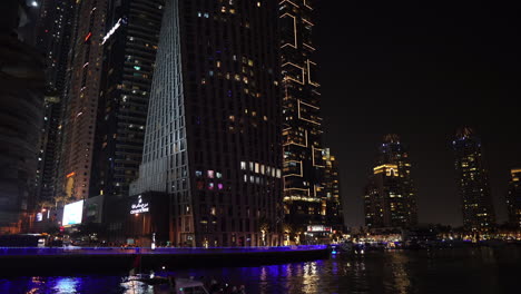 Dubai,-Emiratos-Árabes-Unidos,-Rascacielos-Brillantes-Y-Luz-Sobre-El-Canal-En-El-Puerto-Deportivo-De-Dubai-Por-La-Noche