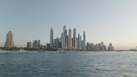 Blick-Auf-Dubai-Von-Der-Jacht,-Sonnenuntergang,-Hohe-Wolkenkratzer,-Weitwinkelaufnahme-Des-Sonnenuntergangs