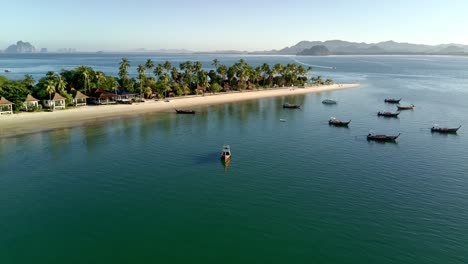Pull-out-drone-shot-of-local-boats-at-Siwalai-beach-on-Koh-Mook-tropical-island-in-Andaman-sea,-Trang,-Thailand