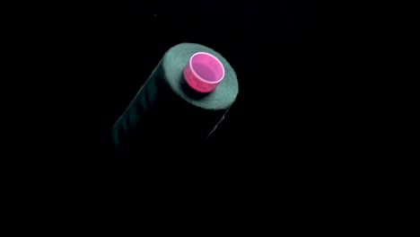 green-thread-on-spool-bobbin-spin-and-unroll-on-black-background-slow-mo
