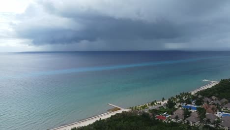 Cozumel-beach-with-a-storm-brewing-over-turquoise-sea-at-dusk,-aerial-view