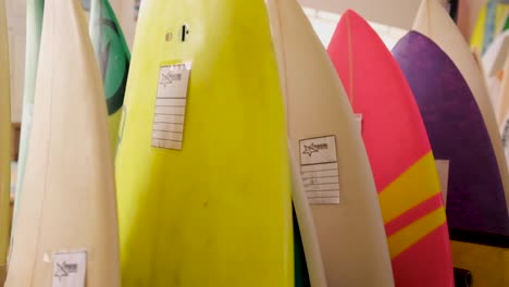 Bunte-Surfbretter-Stehen-In-Einer-Reihe-Zum-Verkauf-Im-Surfshop---Kamerafahrt