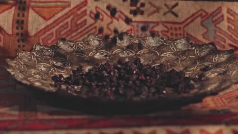 Close-up-shot-of-dried-raisins-falling-into-a-beautifully-decorated-serving-bowl