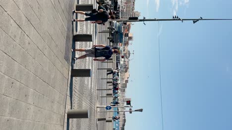 Vertical-shot-of-people-and-street-traffic-by-sunny-port-in-Marseille