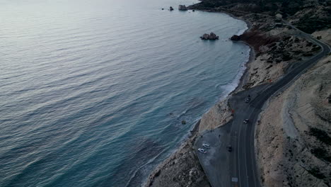 Aerial---coastal-road-near-Aphrodite's-Rock-in-Paphos,-Cyprus,-at-dusk