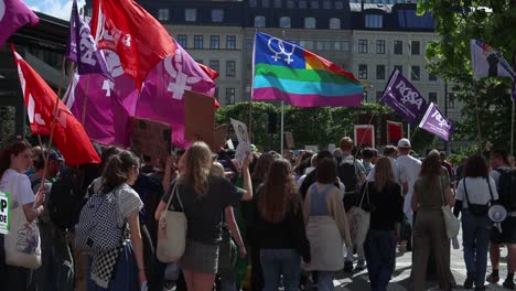 LGBTQ+-and-Women’s-Rights-flags-at-climate-protest-march,-slow-motion