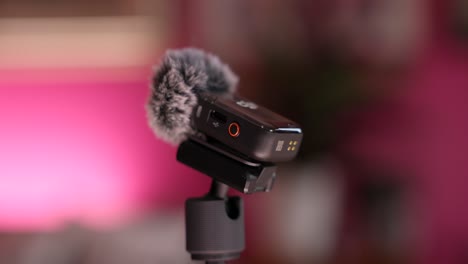 DJI-Wireless-Microphone-With-Windshield-Mounted-On-Tripod-Stick-With-Red-Bokeh-Background