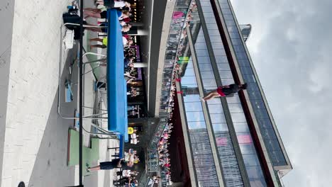 Man-jumps,-does-tricks-and-falls-at-trampoline-show-in-city,-vertical