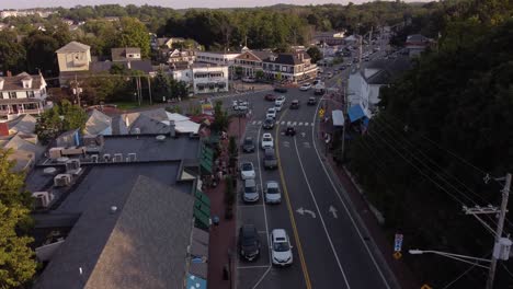 Ogunquit,-Maine-United-States-residential-area-district-aerial-view-of-car-driving-on-a-traffic-road-drone-revealing-cityscape-at-sunset