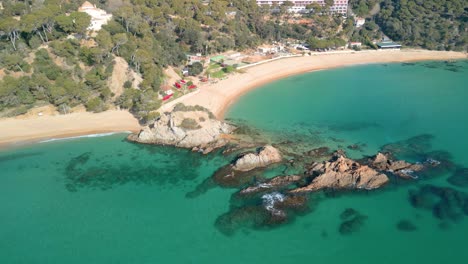 Behold-the-majesty-of-Lloret-De-Mar's-coastal-wonders-through-aerial-imagery,-capturing-the-serene-beauty-of-Santa-Cristina-and-Cala-Treumal