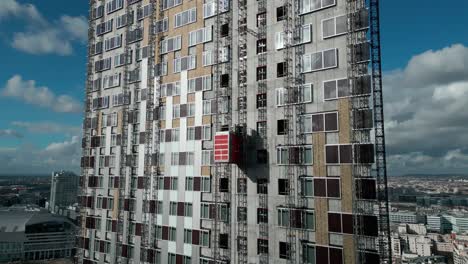 Ascensor-De-Construcción-Descendiendo-Sobre-La-Pared-Exterior-Del-Rascacielos,-La-Défense,-París-En-Francia