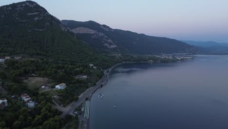 Drone-flight-along-the-coast-in-Greece,-showcasing-villages-and-mountains-in-the-early-morning-before-sunrise