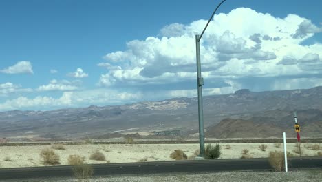 Beautiful-big-white-clouds-in-the-sky-while-driving-down-hot-desert-highway-in-Arizona-tracking-shot-stabilized-handheld