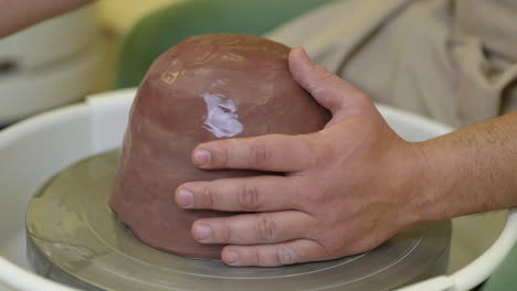 Potter-starting-to-make-ceramic-pot-with-wet-clay-on-pottery-wheel-turntable