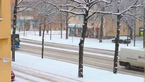 Bus,-car-and-pedestrian-traffic-on-snowy-wintertime-street,-Stockholm