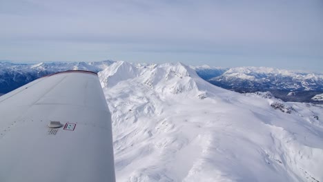 Single-Engine-Piston-Airplane-Wingtip-Flying-Over-Snowy-Mountains