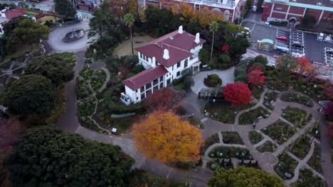 A-historic-building-surrounded-by-autumnal-garden-mazes,-at-dusk,-aerial-view