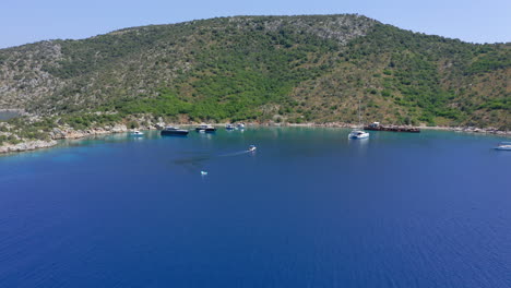 Aérea:-Un-Pequeño-Barco-Con-Turistas-Se-Acerca-A-La-Playa-Del-Naufragio-De-La-Isla-Peristera-En-Espóradas,-Grecia