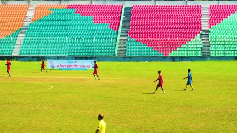 Jugadores-De-Fútbol-En-Un-Campo-Vibrante-Con-Asientos-De-Estadio-Dispuestos-En-Forma-De-Corazón,-Día-Soleado