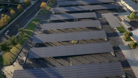 Solar-panels-covering-a-high-school-parking-lot-at-sunset,-aerial-view