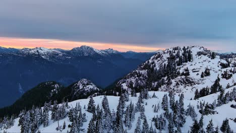 Paisaje-Escénico-De-Montañas-Y-árboles-Nevados,-Colorido-Cielo-Al-Atardecer