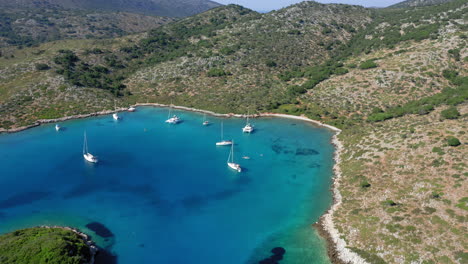 Aerial:-Sailboats-and-catamarans-on-the-bay-of-the-Greek-island-of-Kira-Panagia-in-Northern-Sporades,-Greece