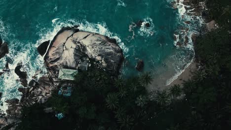 Drone-footage-straight-top-down-view,-ocean-waves-hitting-rocky-beach-hard,-splashing-and-foaming
