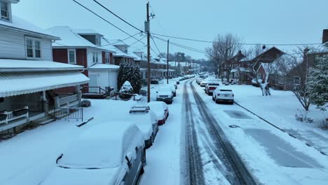 Snow-covered-houses,-cars,-road-in-neighborhood-in-American-town-at-dawn