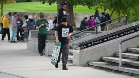 A-Young-Man-Wipes-Out-Crashes-in-front-of-a-crowd-of-teenagers-onlookers-after-riding-his-skateboard-down-a-concrete-rail-at-a-skate-park