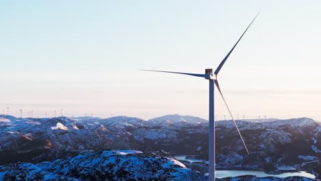 Bessaker,-Trondelag-County,-Norway---Wind-Turbines-Standing-on-a-Snow-capped-Mountain-at-Sunrise---Aerial-Drone-Shot