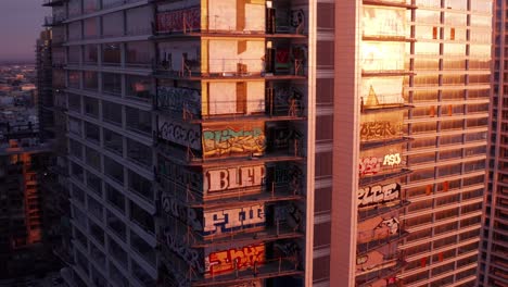 Aerial-close-up-dolly-shot-of-the-extensive-graffiti-art-on-the-Oceanwide-Plaza-buildings-in-downtown-Los-Angeles,-California-at-sunset