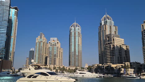 Dubai-Marina,-Luxury-Waterfront-Residential-District,-Boats-and-Yacht-Sailing-Under-Towers