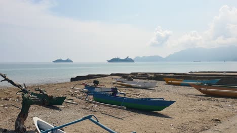 Two-cruise-ships-with-tourist-on-vacation-and-local-fishermen-fishing-boats-on-beach-in-the-capital-city-of-East-Timor,-Southeast-Asia