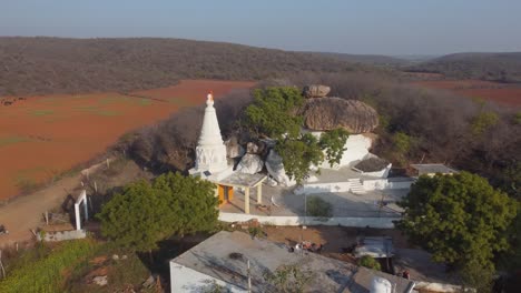 Toma-Aérea-De-Un-Antiguo-Templo-Hindú-Rodeado-De-Granjas-En-Un-Pueblo-De-Madhya-Pradesh,-India