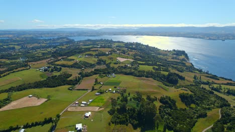 Aerial-Drone-Panoramic-Landscape-of-Lemuy-Island-in-Chiloé-Chilean-Patagonia-Sky-and-Sunshine-reflection-above-Sea-Water-and-Green-Islet-Land