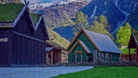 Norse-heritage-park-in-Norway-with-green-roofed-wooden-buildings,-mountain-backdrop,-sunny-day,-timelapse