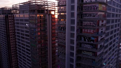 Aerial-reverse-pullback-panning-shot-of-the-abandoned-Oceanwide-Plaza-graffiti-towers-at-sunset-in-downtown-Los-Angeles,-California