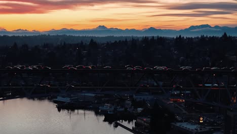 Der-Verkehr-Fließt-über-Die-I5-Brücke-über-Den-Lake-Union-In-Seattle,-Washington,-Vor-Der-Kulisse-Einer-Wunderschönen-Bergkette-Bei-Sonnenuntergang