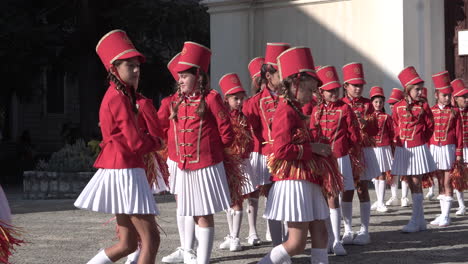 Chicas-En-Majorette-Con-Uniformes-Rojos-Preparándose-Para-La-Práctica-De-La-Ceremonia.