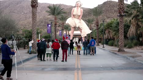Estatua-De-Marilyn-Monroe-En-Palm-Springs,-California,-Con-Gente-Debajo-Con-Video-Inclinándose-Hacia-Arriba