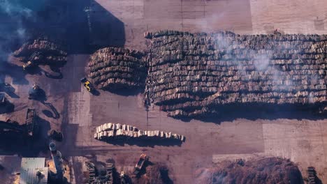 Smoke-Above-Stack-Of-Logs-In-Open-Storage-Area-At-Sawmill-Industry