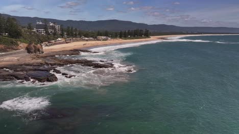 Aerial-of-people-on-the-rocks-with-surf-life-saving-gear-on-the-sand-at-North-Wollongong-Beach