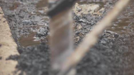 Close-Up-Shot-of-Hot-Gravel-Being-Raked-into-Empty-Pothole