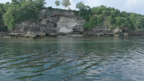 Low-altitude-dolly-drone-shot-of-polluted-water-filled-with-floating-trash-in-the-turqouise-tropical-water-of-Bali-Indonesia