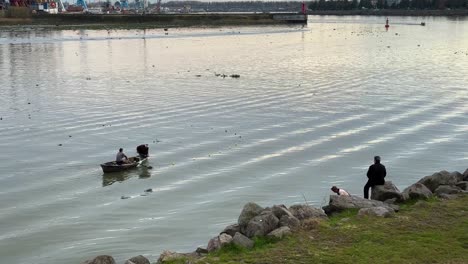 Fila-De-Pescadores-Remar-Un-Viejo-Barco-De-Pesca-Tradicional-De-Madera-Usando-Una-Red-De-Plástico-Para-Pescar-En-El-Puerto-Solo-El-Pescador-Intenta-Expandir-El-Soporte-De-La-Red-Circular-En-La-Playa-Junto-Al-Mar-Bahía-De-Anzali-Vida-Urbana-Irán