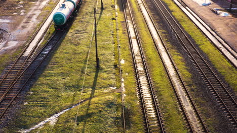 Parallel-raidroad-tracks-with-standing-waggons-and-engine,-aerial-flyover,-Valmiera,-Latvia