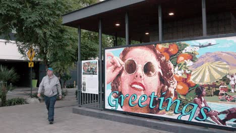 Greeting-mural-in-Palm-Springs,-California-with-man-walking-forward-and-stable-video