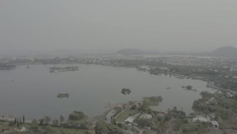 Aerial-drone-view-is-going-to-where-many-different-residence-buildings-and-a-big-lake-are-visible-along-the-river-bank-and-there-are-also-many-trees-around