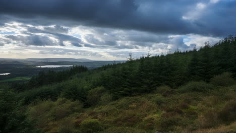 Time-lapse-of-rural-farming-landscape-with-lake,-forest-and-hills-during-a-cloudy-day-viewed-from-above-Lough-Meelagh-in-county-Roscommon-in-Ireland